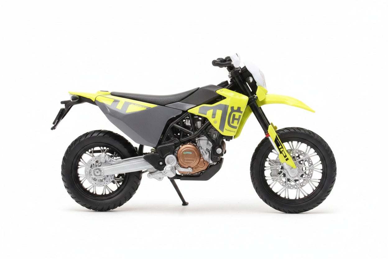 A 1:18 scale toy model of a Husqvarna dirt bike by Majestic, displayed inside its original blue retail packaging. The toy motorcycle features a gray body with bright yellow accents and a detailed engine.