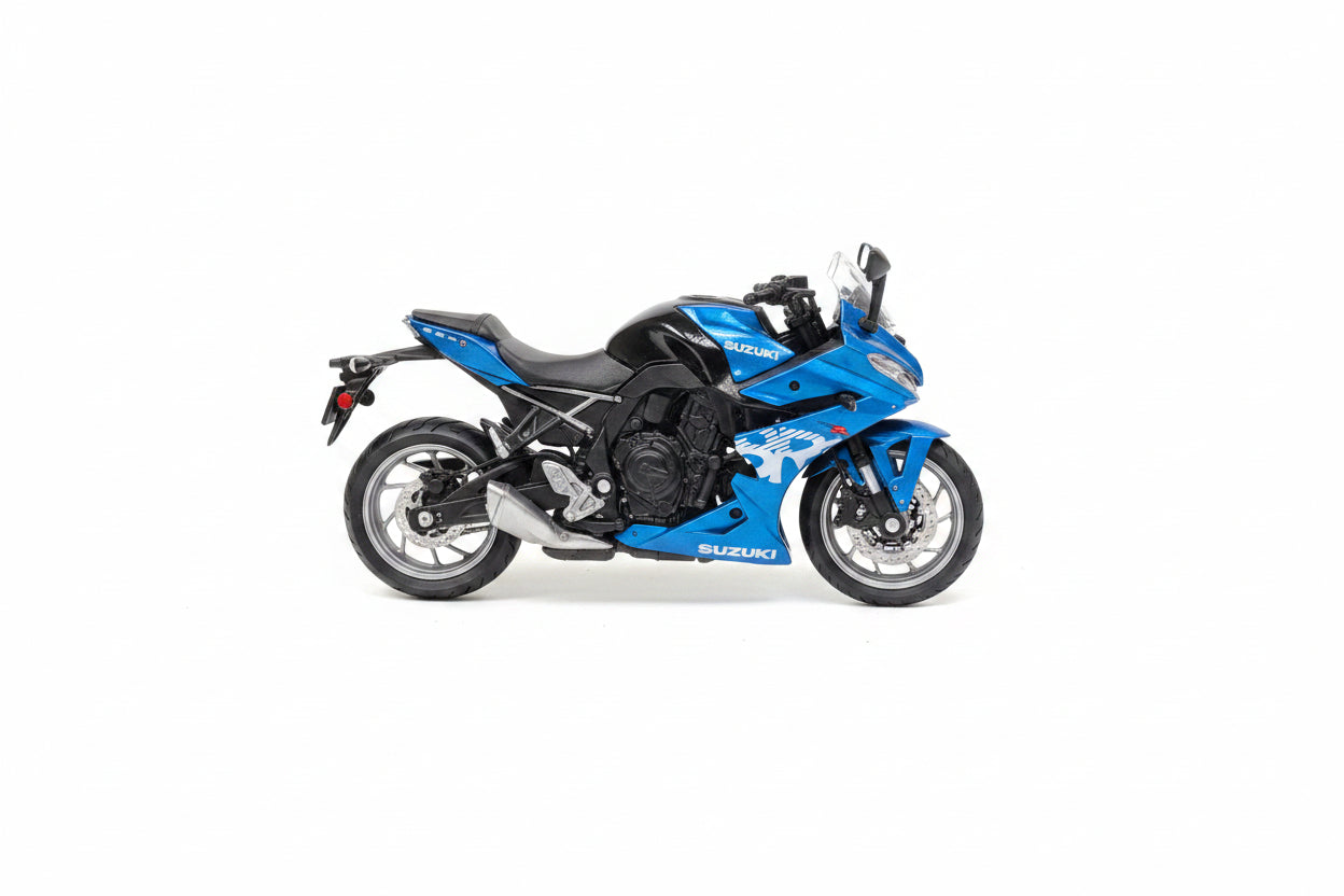 A 1:18 scale diecast model motorcycle by Maisto, featuring a blue and black Suzuki sportbike design, packaged in its original blue retail box with clear plastic blister.