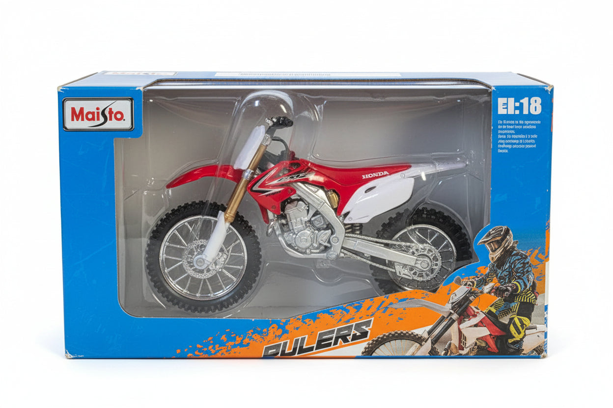 A red and white toy dirt bike inside its blue and orange retail packaging, featuring a clear plastic window and visible 'MotoX' branding.