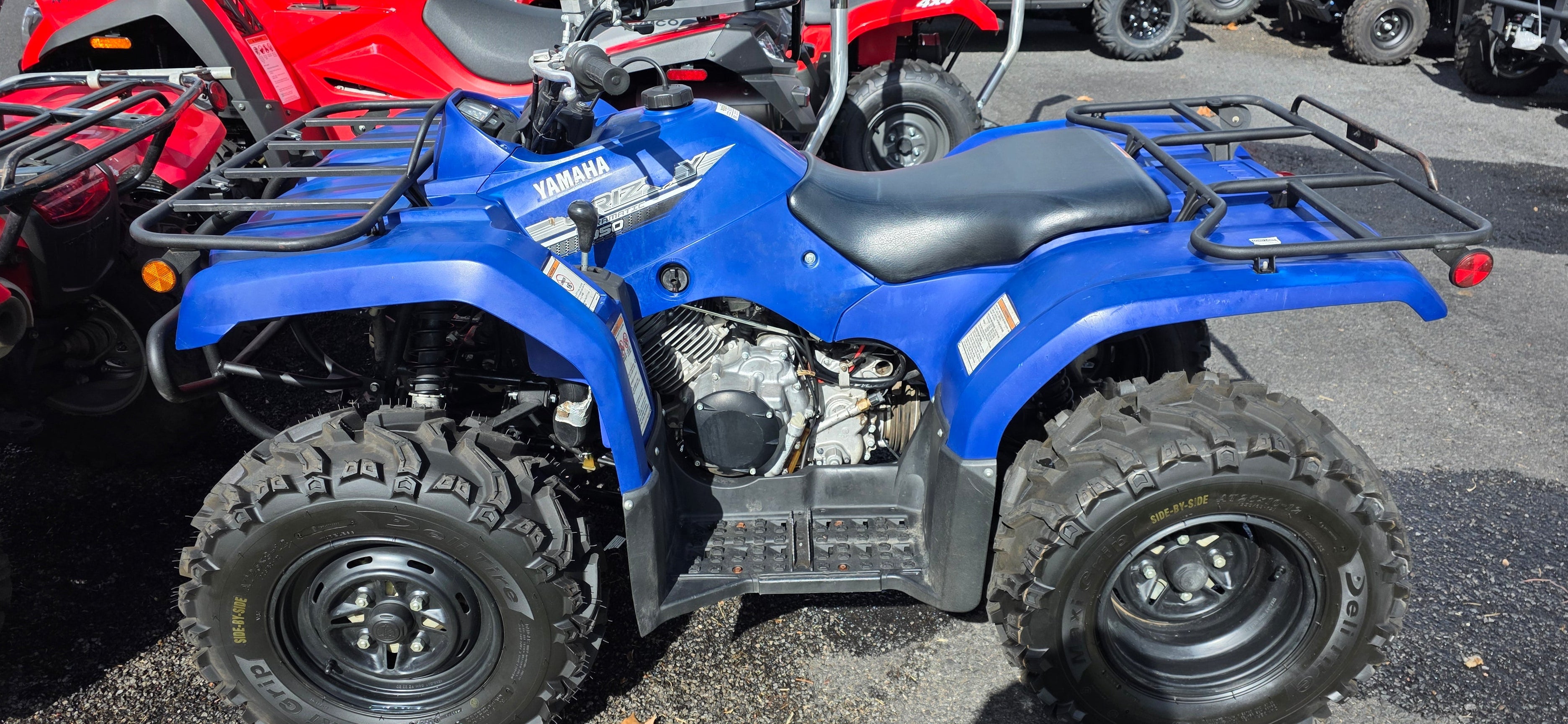 Blue Yamaha ATV parked in a lot with other vehicles.