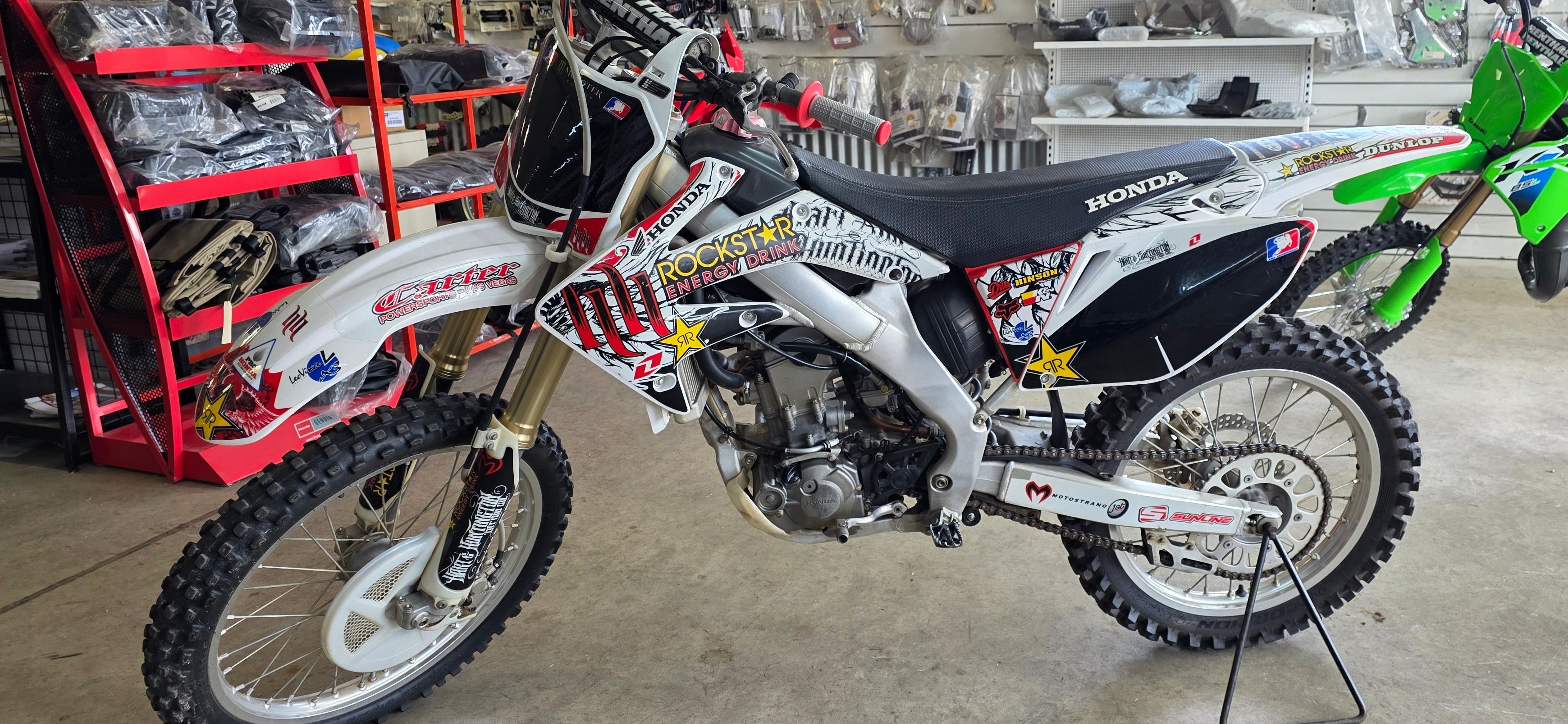 Honda dirt bike with various decals in a garage setting